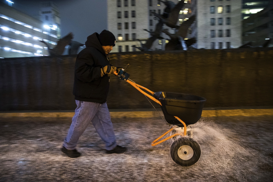 Anthony Trujillo disperses salt on an icy sidewalk during a winter storm Monday in Omaha, Neb. Kansas, Nebraska and Iowa are expected to see a mix of rain and freezing rain on Monday.