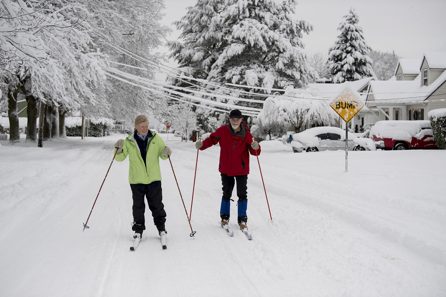 Kate Ketcham, left, and James Lanz of Vancouver take advantage of the snowy weather to do a little cross-country skiing along Northwest Daniels Street on Wednesday morning. Vancouver saw historic snowfalls, with up to a foot of powder falling in some places.