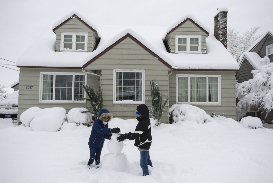 Vancouver resident Kate Mattos, 8, left, and her brother, Kenny, 10, build a snowman in the front yard of their home in Northwest Vancouver on Wednesday morning. Vancouver Public Schools and other districts closed school Wednesday and Thursday in light of the heavy snow.