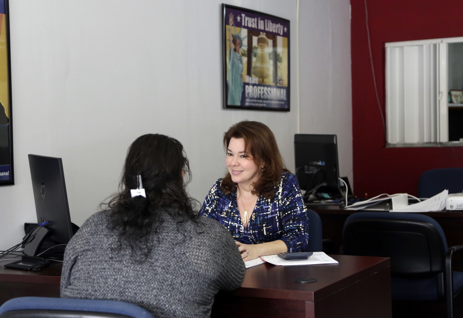 In this Wednesday, Jan. 11, 2017, photo, Maritza Montejo, right, works with a client at Liberty Tax Service in Miami. Tax preparers do a big chunk of America???s tax returns, more than 80 million a year, according to the IRS.