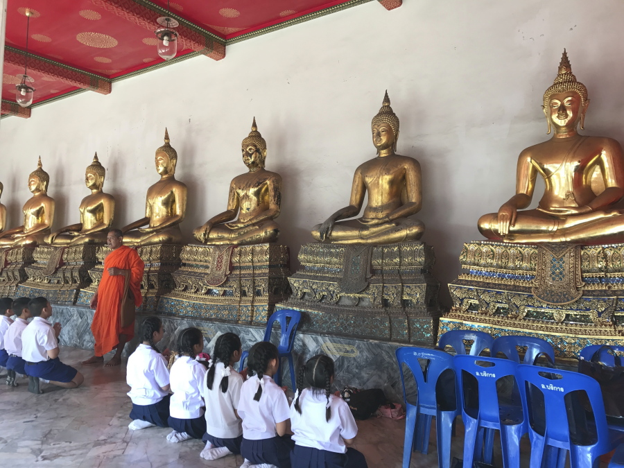 Monks teach schoolchildren religious incantations at Wat Pho, or the Temple of the Reclining Buddha, in Bangkok. Between lessons, the kids waved and called greetings to tourists.