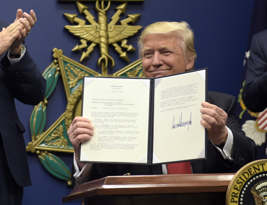 President Donald Trump shows his signature on an executive action on rebuilding the military Friday at the Pentagon in Washington.