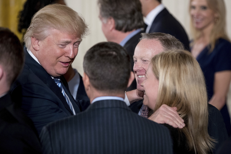 President Donald Trump, left, congratulates White House Press Secretary Sean Spicer, second from right, and other White House senior staff during a swearing-in ceremony Sunday in the East Room of the White House.