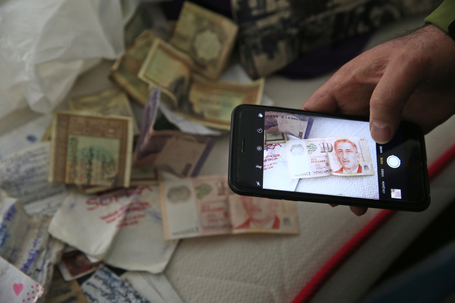 A member of the media uses his mobile phone to take pictures of belongings including banknotes of different currencies on a bed inside the flat where a suspect of New Year&#039;s Day nightclub attack was arrested during an overnight police raid, in Istanbul, on Tuesday.