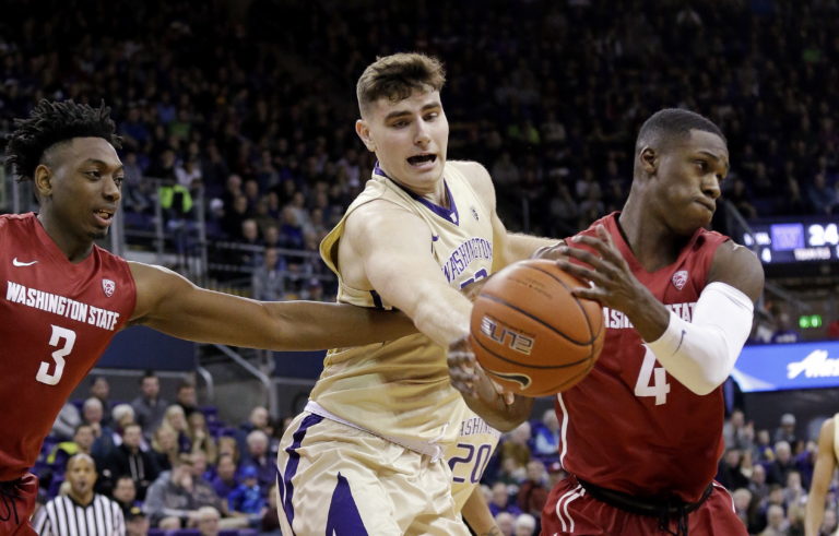 Washington's Sam Timmins, center, reaches for the ball between Washington State's Robert Franks (3), an Evergreen High grad, and Viont'e Daniels (4) in the first half  Sunday, Jan. 1, 2017, in Seattle.