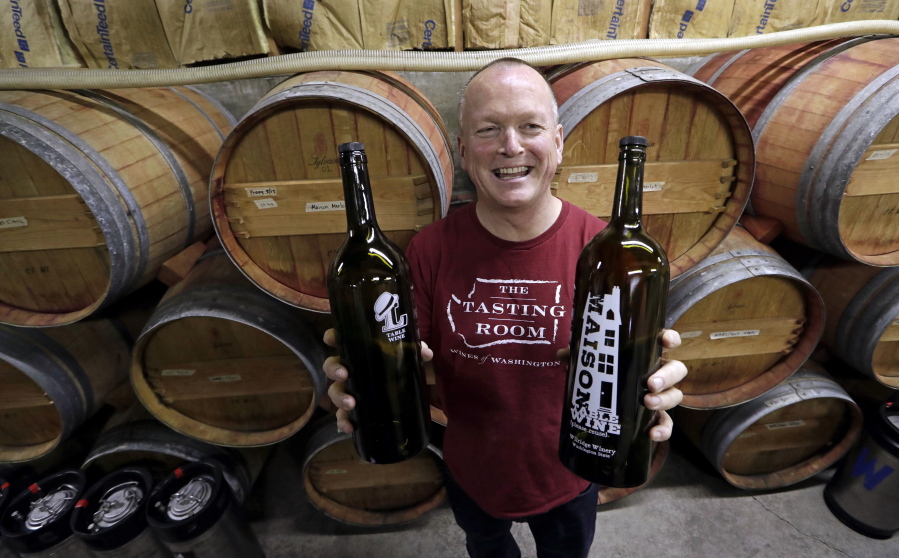 In this photo taken Tuesday, Jan. 10, 2017, winemaker Paul Beveridge displays the type of wine &quot;growler&quot; bottle he would like to see available to consumers, at his winery in Seattle.  Wine drinkers are one step closer to being able to purchase and refill their favorite pours in reusable growlers closer to home instead of making a trip to the winery. Some state winemakers are pushing House Bill 1039 as a way to expand wine sales and reduce the carbon footprint of wine bottles. If approved, consumers would be able to bring or buy refillable growlers at any business that has the license to sell wine.