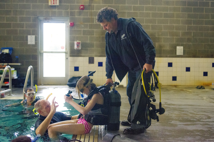 Billy Snook, co-owner of Seven Seas Scuba, helps student Heidi Pratt, 12, out of the pool at Cascade Athletic Center.