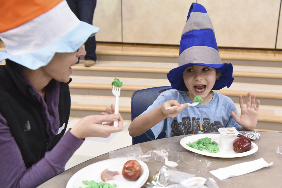 First-grader Eli Deets gets ready to take a bite of green eggs with his mom, Brooke Deets, on Monday at Sarah J. Anderson Elementary School. The school kicked off Read Across America week with a colorful breakfast in honor of Dr. Seuss&#039; beloved children&#039;s books.