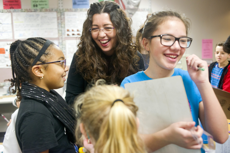Kimberley Astle laughs with students Kaelyn Thomas, 10, left, and Siena Low, 11, while helping them with a science experiment.