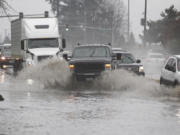 Drivers navigate standing water Sunday afternoon on state Highway 503 near Northeast 87th Street in the Orchards area.
