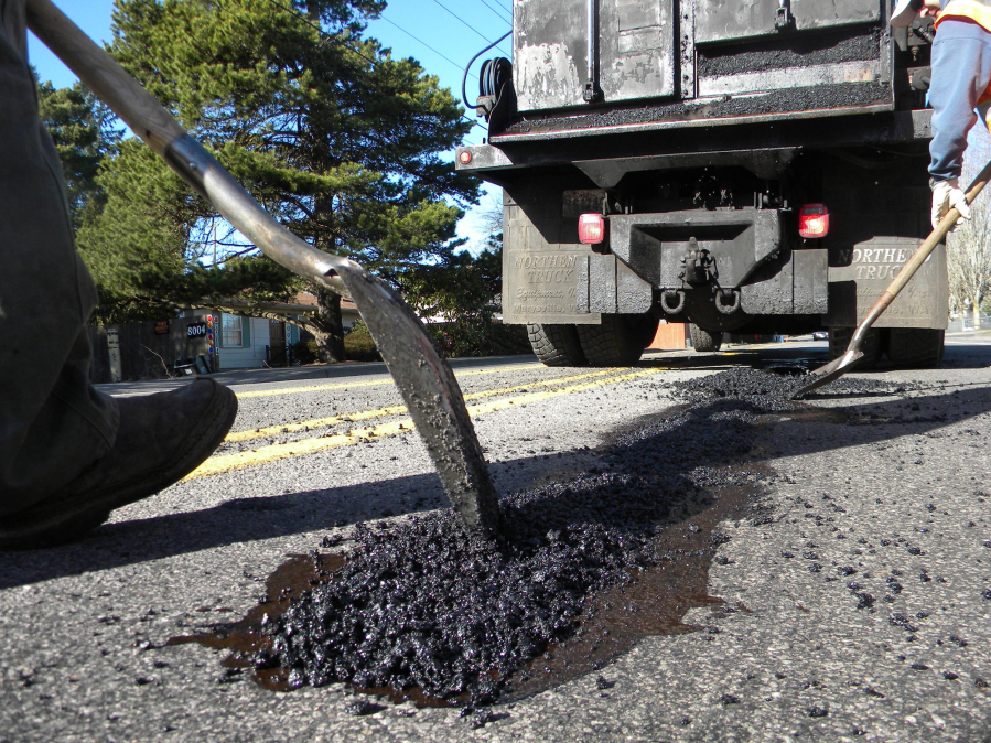 A Clark County Public Works crew shovels asphalt into a pothole on Northeast 130th Avenue.