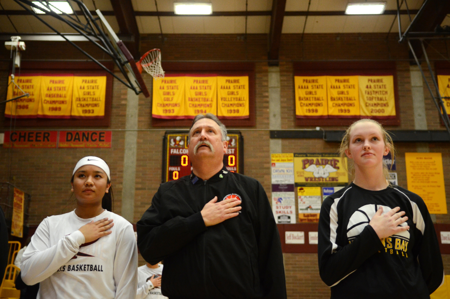 Rick Stover is flanked by Prairie senior Grace Prom, left, and Hudson&#039;s Bay senior Sharon Hanson during the national anthem before a basketball game at Prairie on Thursday. It&#039;s tradition that started last season with players flanking Stover to help remember the sacrifice Stover&#039;s late son Chris made in service to his country.
