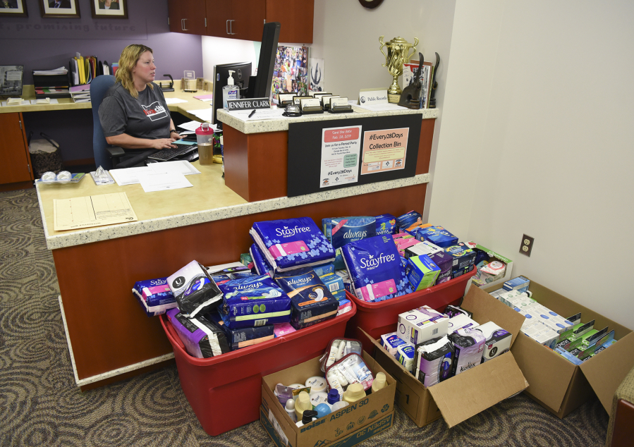 Jenn Clark, administrative assistant in the Clark County council office, works at her desk Friday where boxes of feminine hygiene donations for Share are being stored. A team of volunteers is aiming to collect 3,000 boxes of pads and tampons for Share by Tuesday.