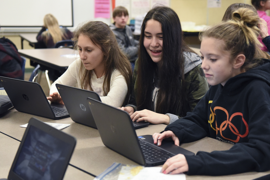 Seventh-graders Katerina Yarosh, left, Rachel Knight, and Emma Jensen work on their new Chromebooks during study hall at Pleasant Valley Middle School on Thursday.