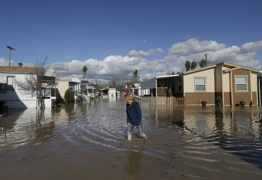 A man walks down a flooded street Wednesday in South Bay Mobile Home Park in San Jose, Calif.