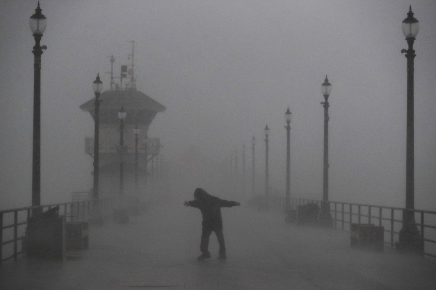 A man struggles against heavy wind and rain Friday on a pier in Huntington Beach, Calif. (JAE C.