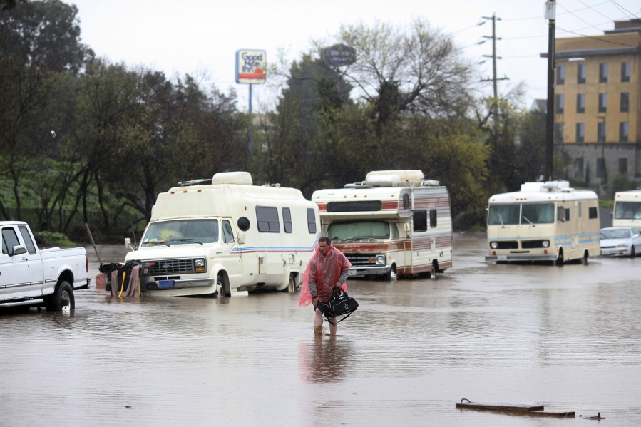 A man who lives in his RV, which was parked in the 300 block of Griffith Street in Salinas, Calif., walks through the flooded street on Monday.