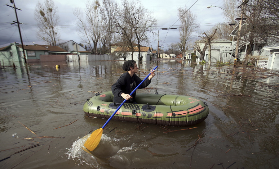 Bruce Alden of Lakeport, paddles his way across Esplanade Street to get some waders from friends in a flood Tuesday in Lakeport, Calif.
