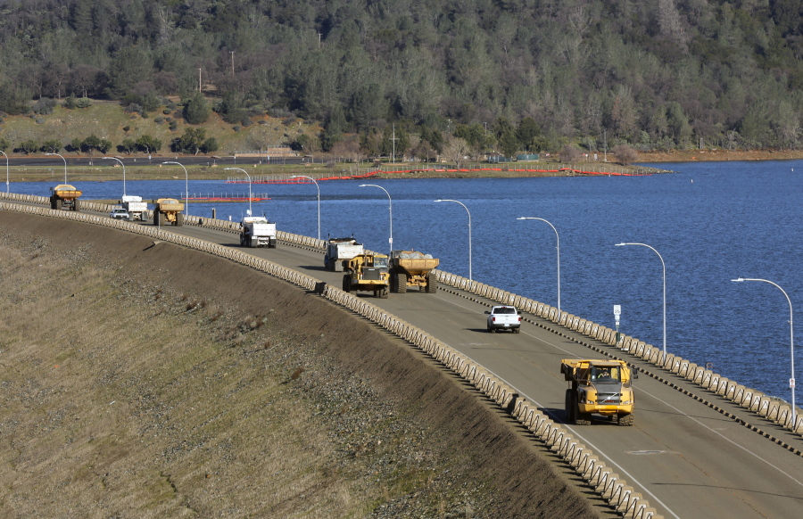 Trucks traverse the Oroville Dam roadway as the effort to stabilize the emergency spillway continues Tuesday in Oroville, Calif. Officials say the decision to lift the evacuation order for nearly 200,000 people living below a damaged dam in California has taken into account updated weather forecasts. A storm later this week is expected to be colder, with less rain.