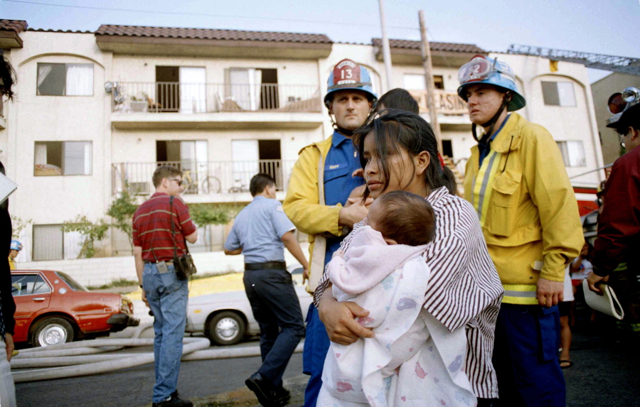 May Isabela Diego holds her infant son Pedro in the aftermath of a May 3, 1993, fire in an apartment complex in the Westlake section of Los Angeles. Diego had to drop her two children out of a window as fire threatened their safety. Police have arrested several people for the 1993 fire that killed 10 people, including seven children.