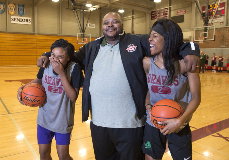 Tiarra, left, and Tianna Brown crack up while posing with their father, Tim, for a photo at the gym in Bethel High School in Spanaway.