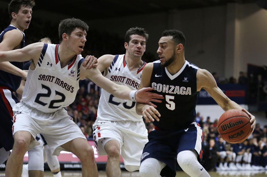 Gonzaga&#039;s Nigel Williams-Goss, right, drives the ball against Saint Mary&#039;s Dane Pineau (22) and Joe Rahon, center, during the first half of an NCAA college basketball game Saturday, Feb. 11, 2017, in Moraga, Calif.
