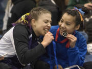 Columbia River's Sarah Ellis, left, and Ridgefield's Kylee Tjensvold bite into their medals after the awards for the Balance Beam event during the 1A/2A/3A State Gymnastics Finals Friday , Feb. 17, 2017, in Tacoma, Wash. Ellis placed 1st and Tjensvold took home 2nd.