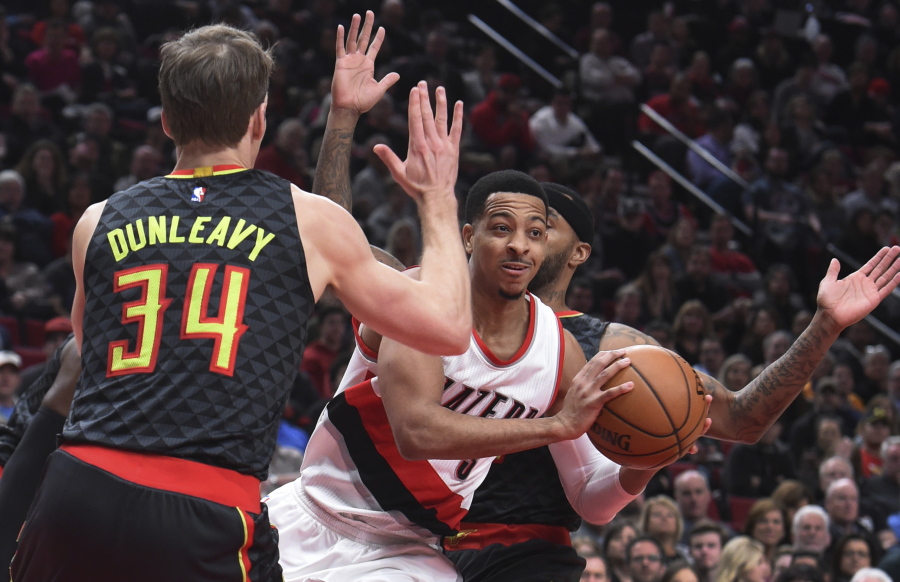 Portland Trail Blazers guard C.J. McCollum passes the ball as he drives to the basket on Atlanta Hawks guard Mike Dunleavy during the first half of an NBA basketball game in Portland, Ore., Monday, Feb 13, 2017.