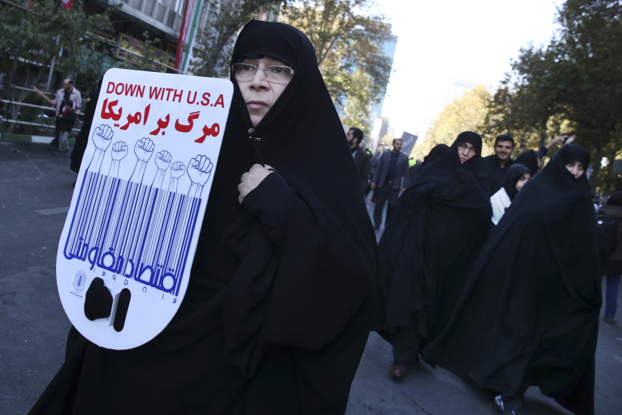 An Iranian demonstrator holds an anti-U.S. placard in a state-organized annual rally in front of the former U.S. Embassy in Tehran, Iran, marking 37th anniversary of the seizure of the embassy by militant Iranian students.