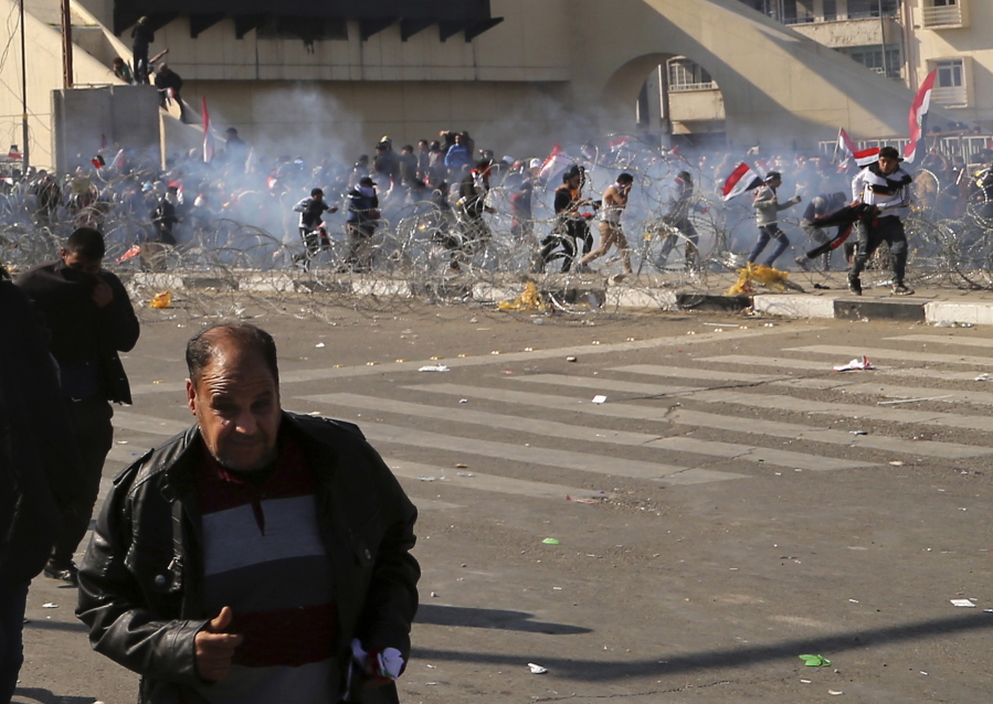 Protesters run from tear gas fired by security forces, during a demonstration against corruption by followers of Iraq&#039;s influential Shiite cleric Muqtada al-Sadr in Tahrir square, Baghdad, Iraq, Saturday, Feb. 11, 2017.
