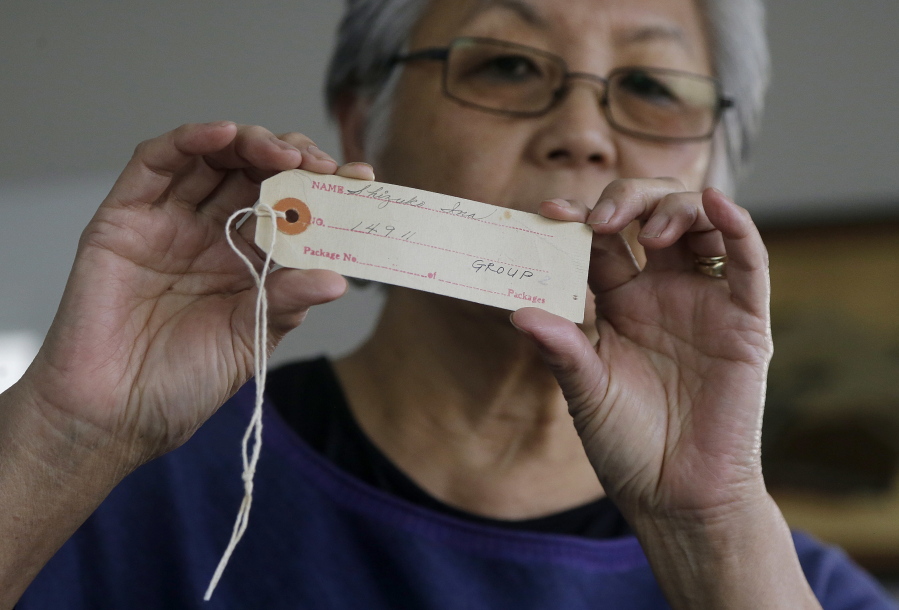 Satsuki Ina holds up an internment identification tag Feb. 10 at her home in Oakland, Calif. The tag was issued to her mother, Shizuko Ina.