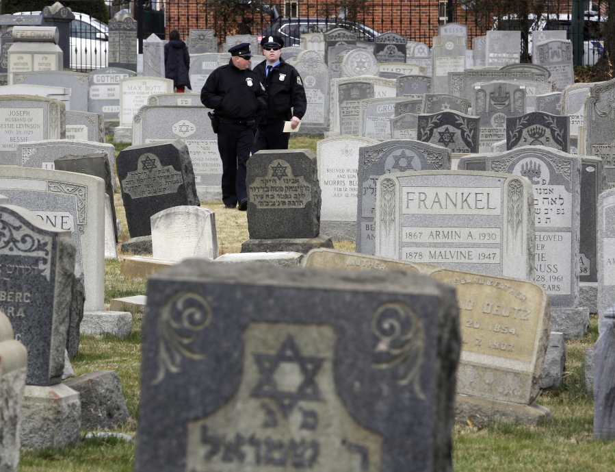 Philadelphia Police walk through Mount Carmel Cemetery on Monday in Philadelphia. More than 100 headstones have been vandalized at the Jewish cemetery in Philadelphia, damage discovered less than a week after similar vandalism in Missouri, authorities said.