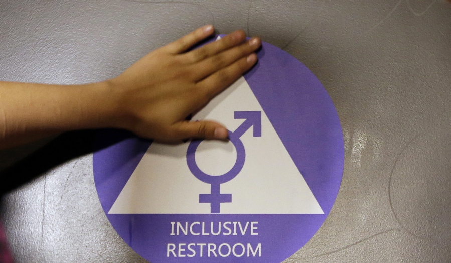 A new sticker is placed on the door at the ceremonial opening of a gender-neutral bathroom at Nathan Hale High School in Seattle.