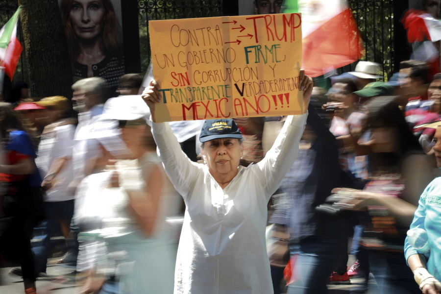 A woman holds up a banner Sunday that reads, in Spanish, &quot;Against Trump,&quot; during a march in Mexico City demanding respect for Mexico and its migrants, in the face of perceived hostility from the administration of U.S. President Donald Trump. About 20,000 people marched, many dressed in white.