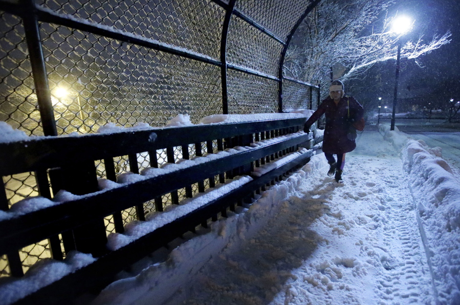 A person crosses a bridge near a commuter rail station Sunday in Wellesley, Mass. Another winter blast of snow and strong winds moved into the Northeast on Sunday, to the delight of some and the consternation of others, just days after the biggest storm of the season dumped up to 19 inches of snow in the region.