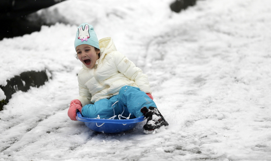 Eva Covert, 6, sleds on a hilly street in Seattle, Monday, Feb. 6, 2017. A snowstorm that blanketed Seattle and western Washington state into Monday morning prompted widespread school closures, flight cancellations and power outages. (AP Photo/Ted S.