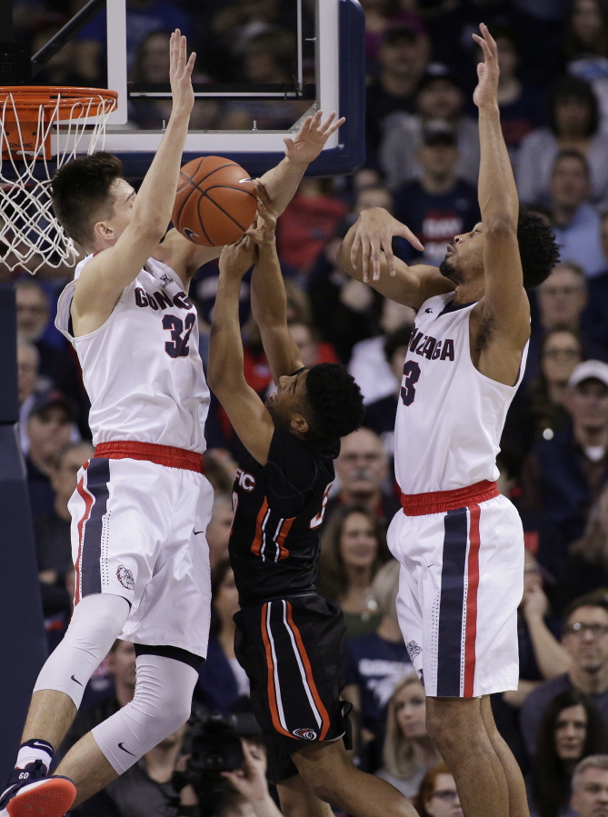 Pacific guard K.J. Smith, center, tries to shoot between Gonzaga forward Zach Collins (32) and forward Johnathan Williams (3) during the first half of an NCAA college basketball game in Spokane, Wash., Saturday, Feb. 18, 2017.