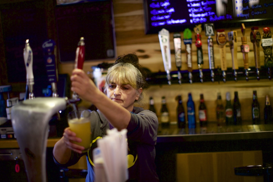 Judy Unquera, a bartender at the Long Branch, pours a beer at the bar in Monroe, Ore., on Nov. 18, 2014. State lawmakers consider reevaluating service industry worker rights.