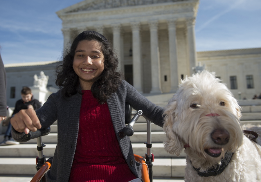 Ehlena Fry of Michigan, sits with her service dog Wonder, while speaking to reporters outside the Supreme Court in Washington in October.