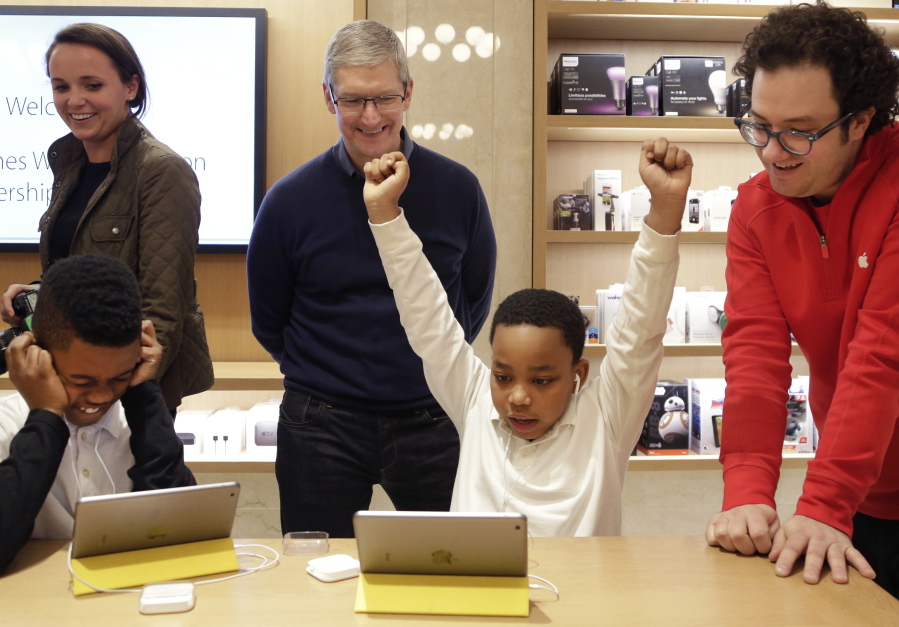 Jaysean Erby raises his hands Dec. 9, 2015, as he solves a coding problem while Apple CEO Tim Cook watches from behind at an Apple Store in New York as Apple hosted Hour of Code events around the world.