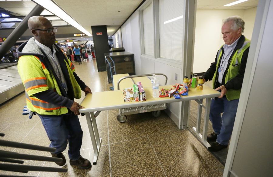 Port of Seattle workers Aaron Washington, left, and Tracy Jenkins carry a table and snacks into a room near where passengers arrive on international flights at Seattle-Tacoma International Airport. (Photos by Ted S.