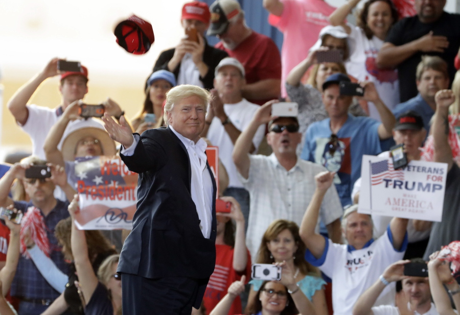 President Donald Trump tosses a hat into the crowd at a rally Saturday at Orlando-Melbourne International Airport in Melbourne, Fla.