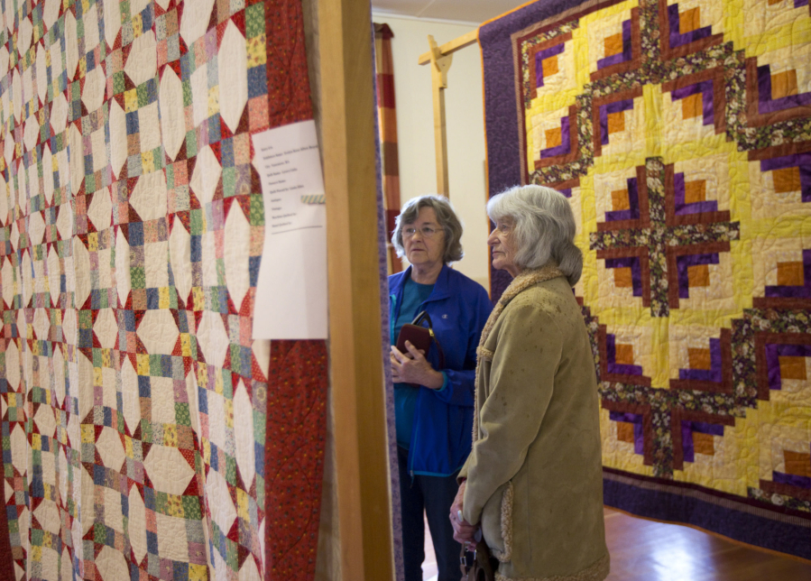 Evelyn Dobbins, left, and Ruth Ham examine quilts on display as part of the North Clark County Historical Museum&#039;s quilt show Sunday in Amboy. These quilts were set up at the Mt. Valley Grange hall.