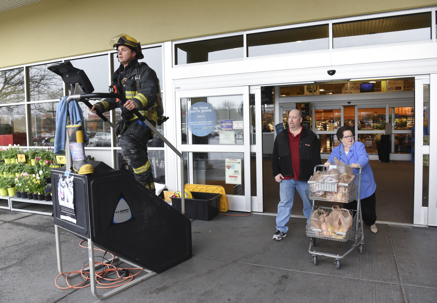 Larry Langdon, center, and Sheila Langdon, right, exit the Fisher&#039;s Landing Fred Meyer on Southeast McGillivray Boulevard, where Vancouver firefighter Scott Woodhouse uses a stair climber as part of a fundraiser for the Leukemia &amp; Lymphoma Society on March 3.