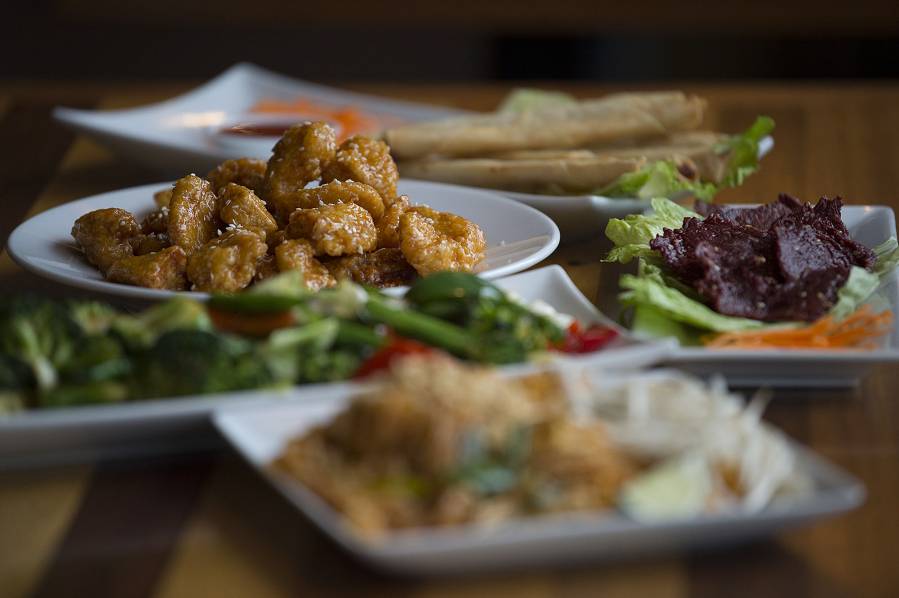 Crispy orange chicken, clockwise from dish in focus, is served with egg roll fries, crispy beef, Pad Thai and Buddha mix vegetables at Fast Thai in Southeast Vancouver.