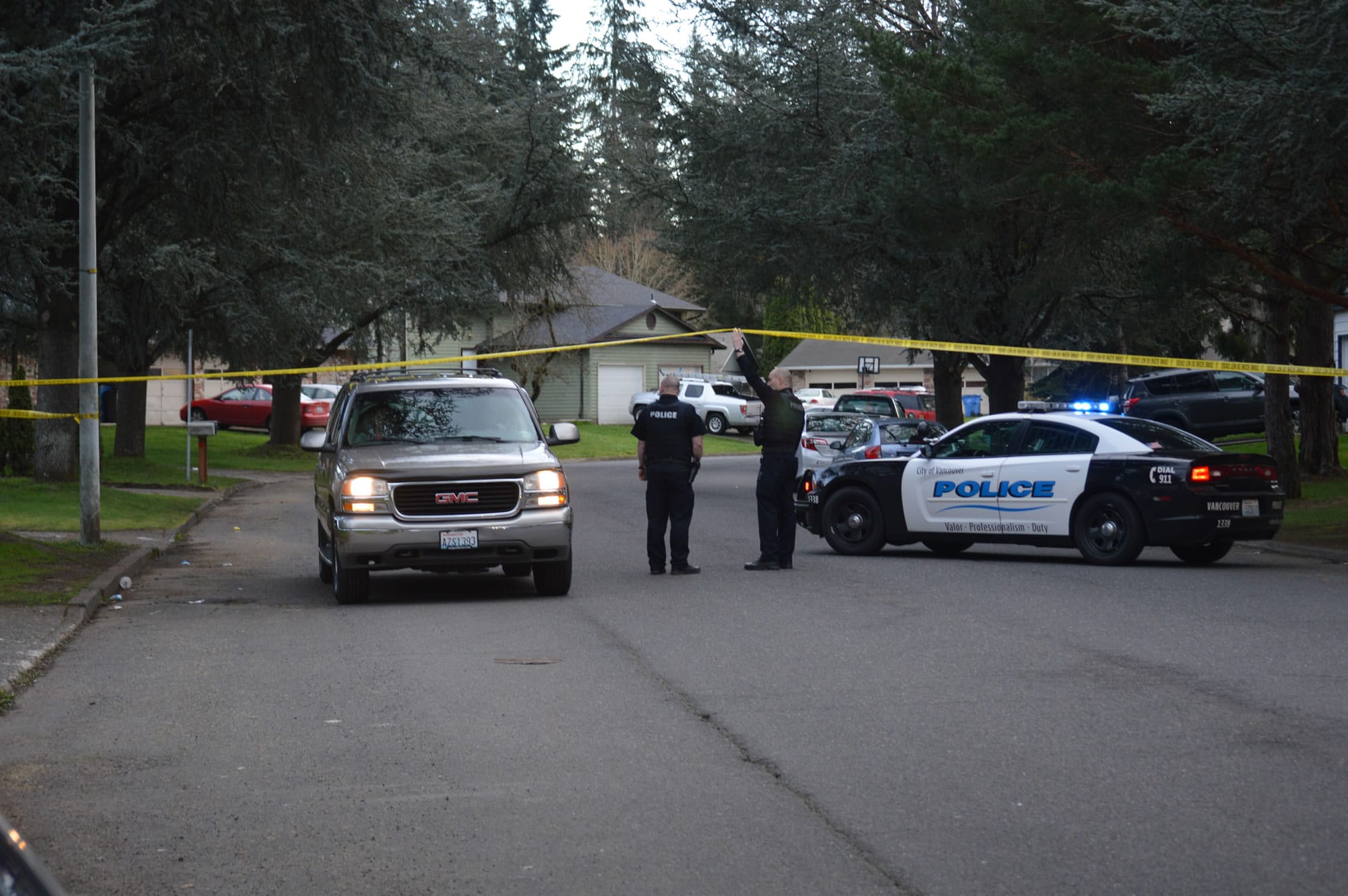Officers direct a neighboring resident past a roadblock set up for a shooting investigation down the road Sunday evening on Northeast 140th Avenue. The Vancouver Police Department said officers responded to a report of a shooting in the area and found two dead men at a residence in the 1500 block.