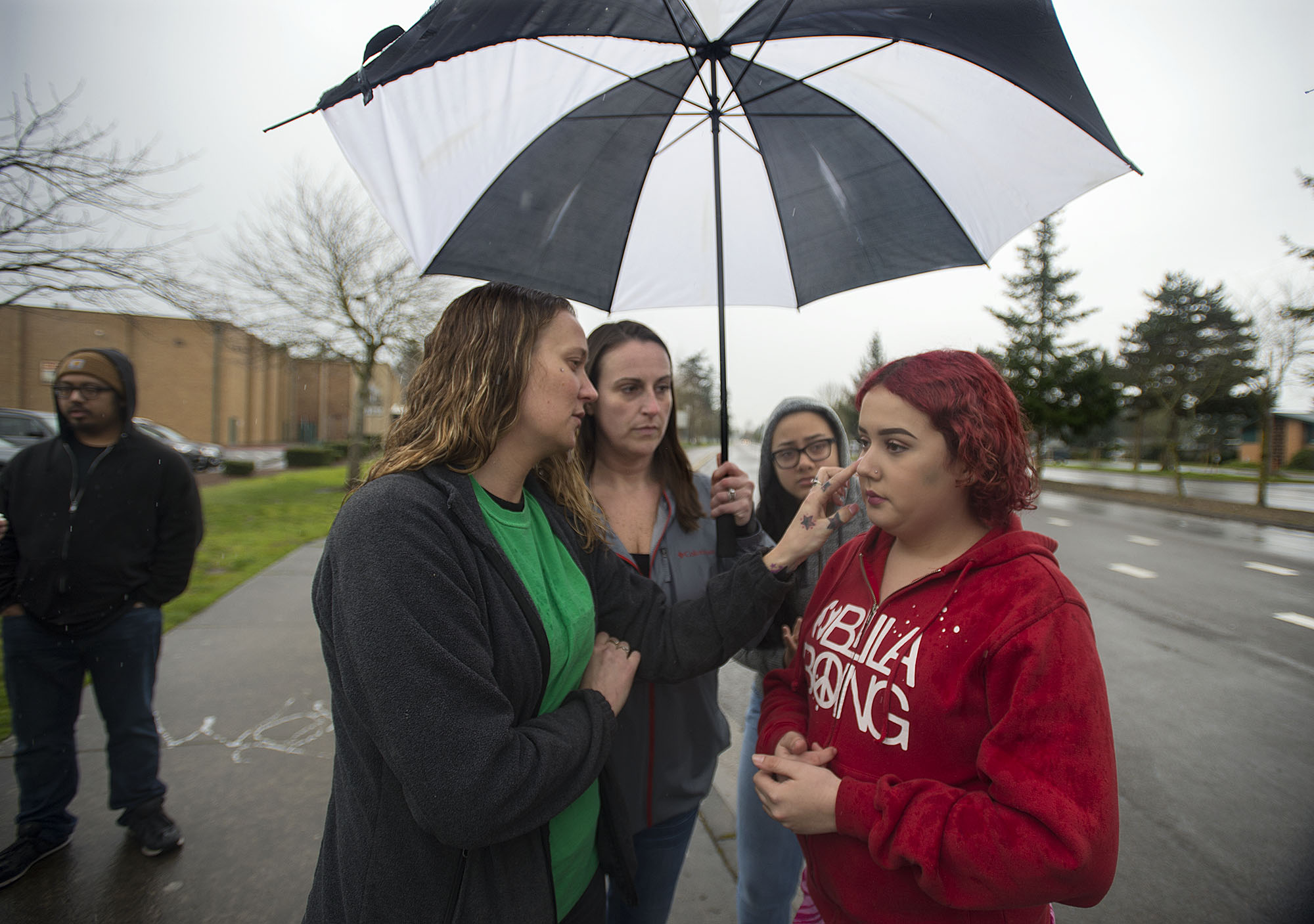 Lindsey Smith, 13, right, is joined by her mom, Carrie Smith, left, her aunt, Leslie Goodnight, and family friend, Jasmine Freeman, as they look over injuries they say she sustained after a fellow student punched her in the face Wednesday, as seen outside McLoughlin Middle School on Friday afternoon, March 17, 2017. School district officials announced Vancouver police are investigating the allegations.