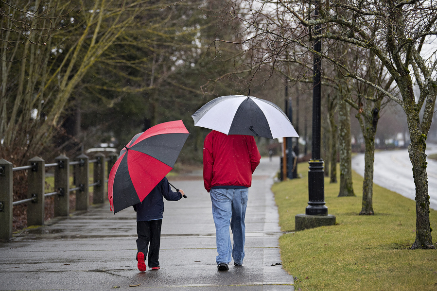 Beckett Ince, 8, of Ridgefield, left, keeps in step with his dad, Jubal, as they enjoy a soggy stroll together along the Vancouver Waterfront on the afternoon of Feb. 8.