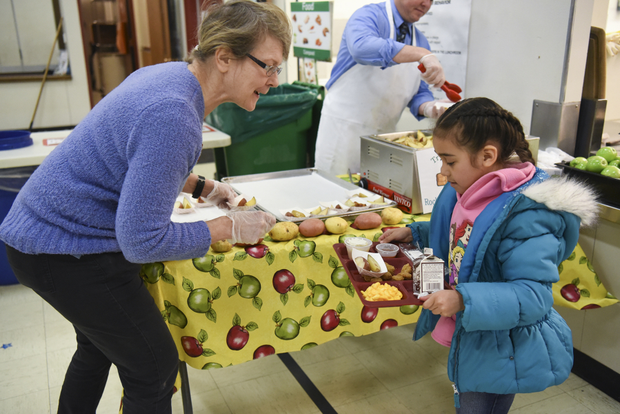 Marty Fields, nutrition educator for SNAP-Ed, serves roasted potato wedges to kindergartner Samantha Vargas.