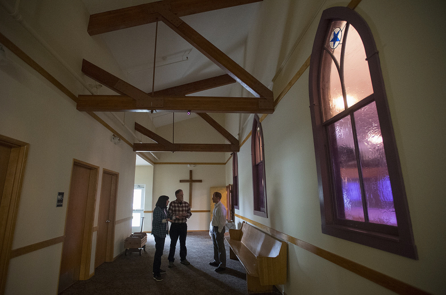 Centennial committee members Linda Bieker and Dean Sutera, from left, discuss plans with the Rev. Korey Finstad, pastor of Bethel Lutheran Church. The windows behind him mark what had been an exterior wall of the original church, which was built in 1921. The Brush Prairie church is celebrating the 100th anniversary of its formation.